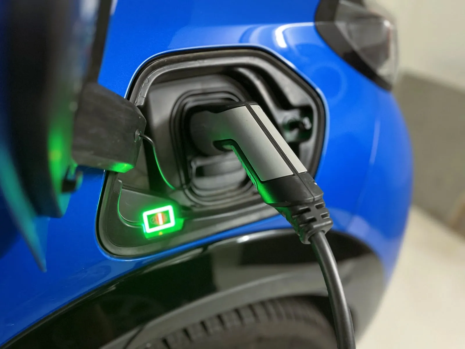 Wallbox an einer Hauswand, daneben ein ladendes Elektroauto